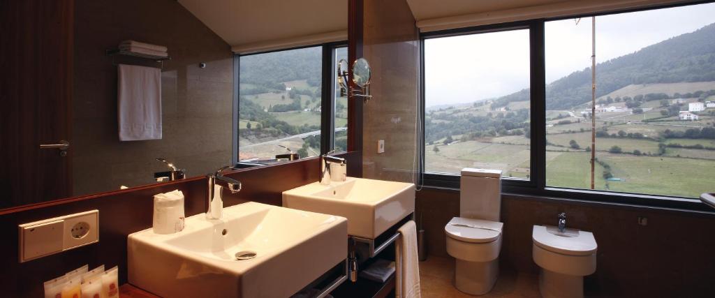 a bathroom with two sinks, a toilet and a bathtub at Hotel Palacio de Merás in Tineo