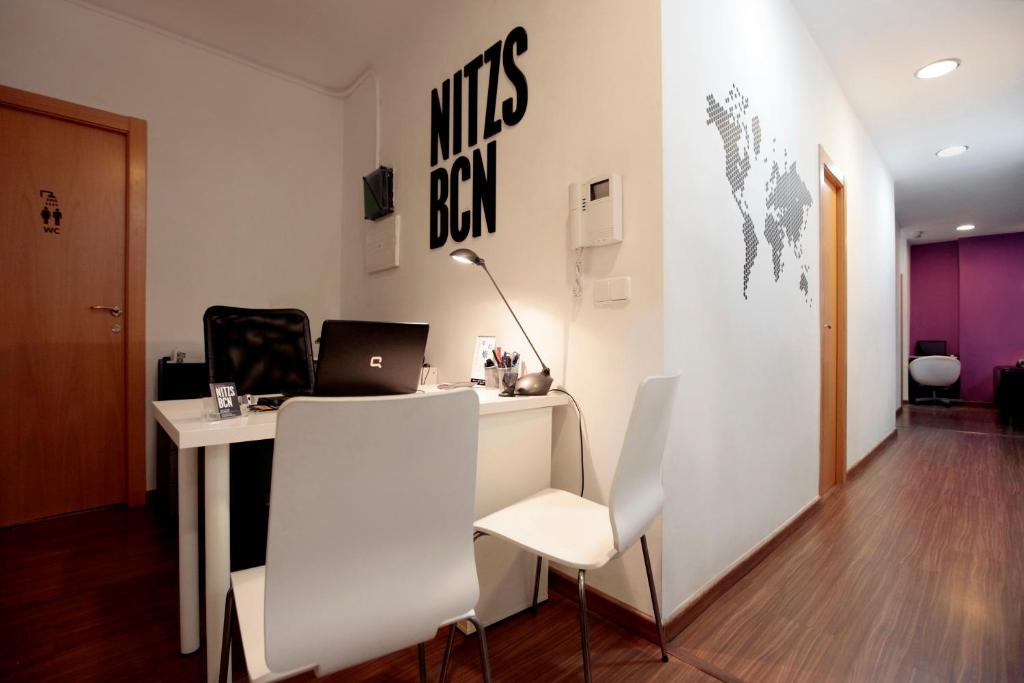 a room with a table, chairs, and a laptop on the wall at Hostal Nitzs Bcn in Barcelona