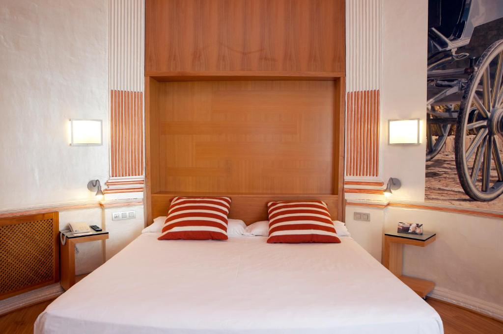 a bedroom with a bed with two red and white pillows at Itaca Jerez by Soho Boutique in Jerez de la Frontera