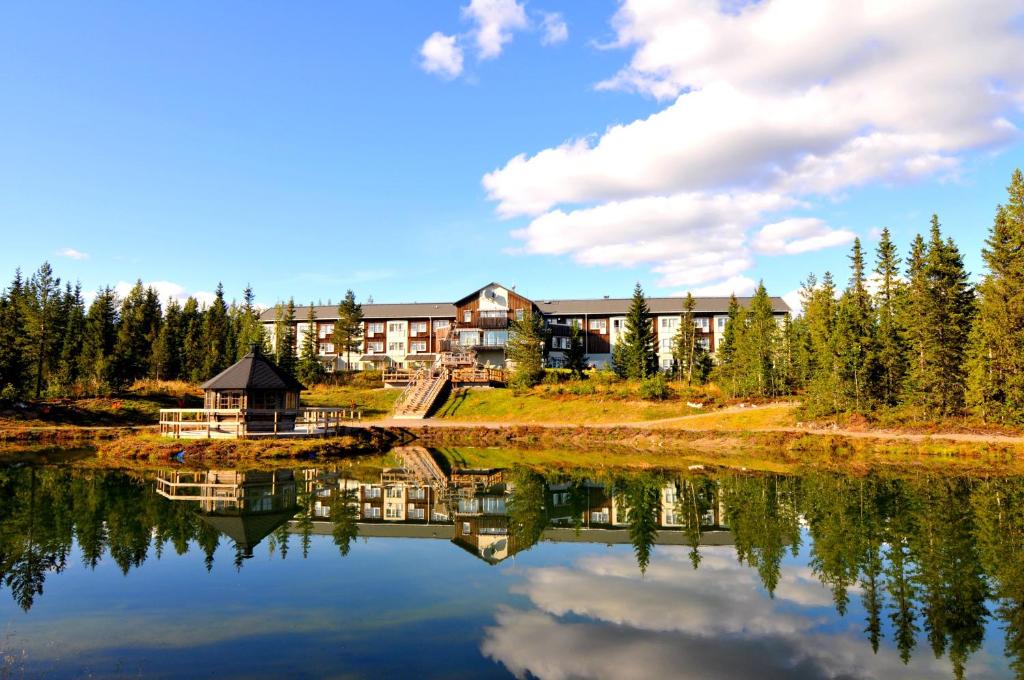 a resort is reflected in the water of a lake at Källan Hotell Spa Konferens in Åmliden