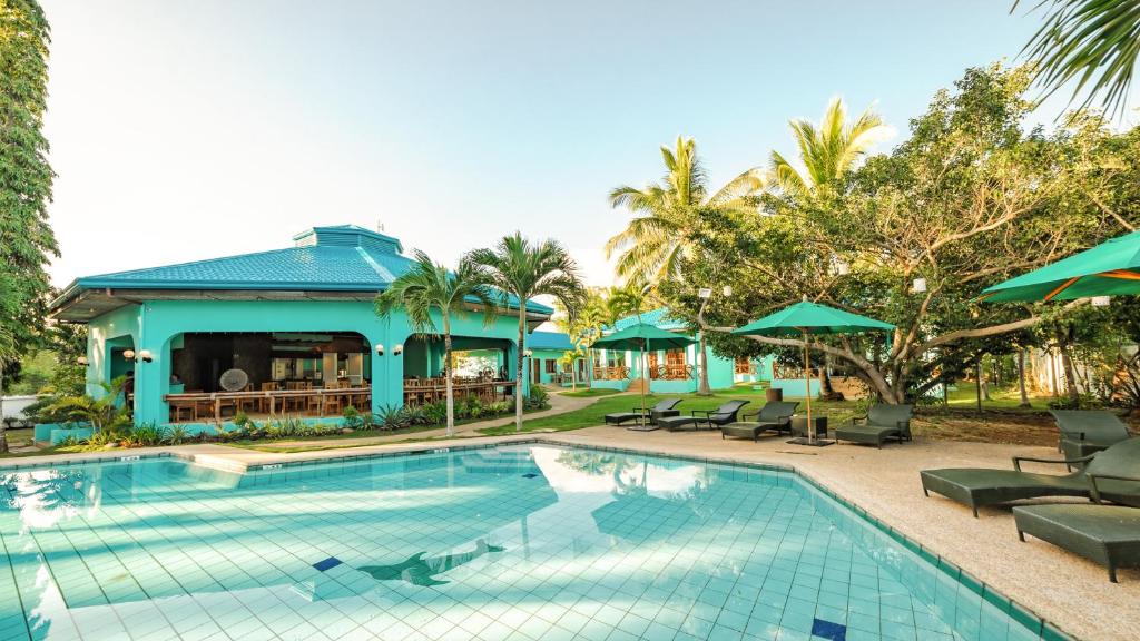 uma piscina num resort com cadeiras e guarda-sóis em Bohol Sea Resort em Panglao City