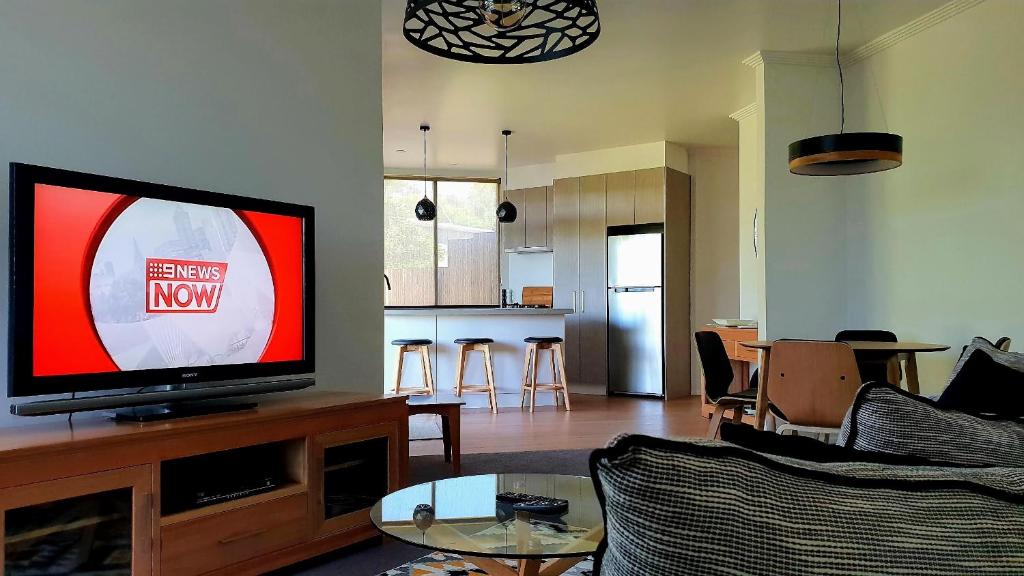sala de estar con TV de pantalla plana en un centro de entretenimiento en Number 9 Leisure Stay, en Port Campbell