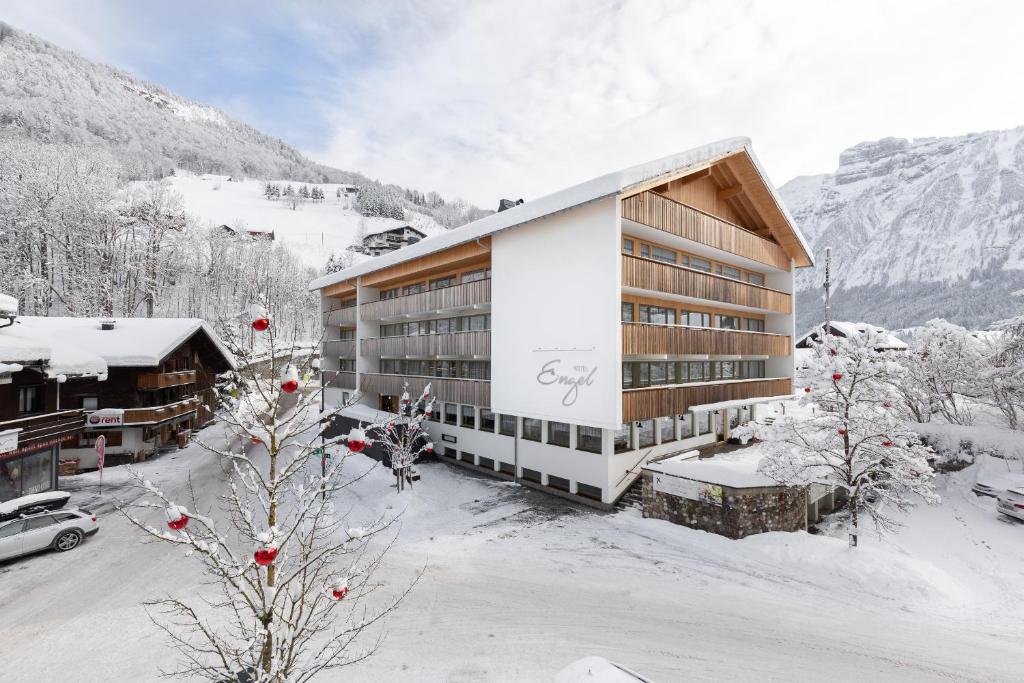 ein großes Gebäude im Schnee mit einem Berg in der Unterkunft Hotel Engel in Mellau