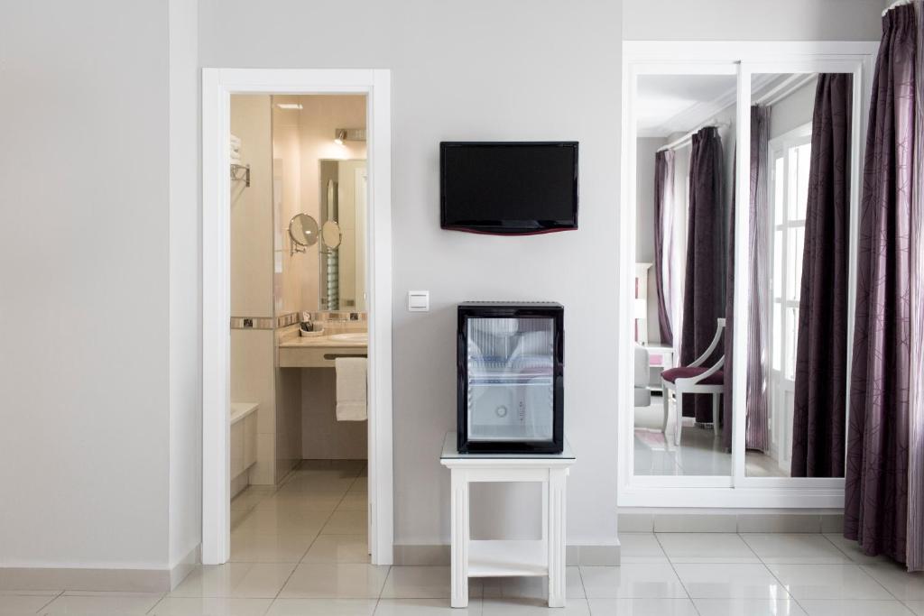 a living room with a tv on a wall at Hotel Plaza Cavana in Nerja