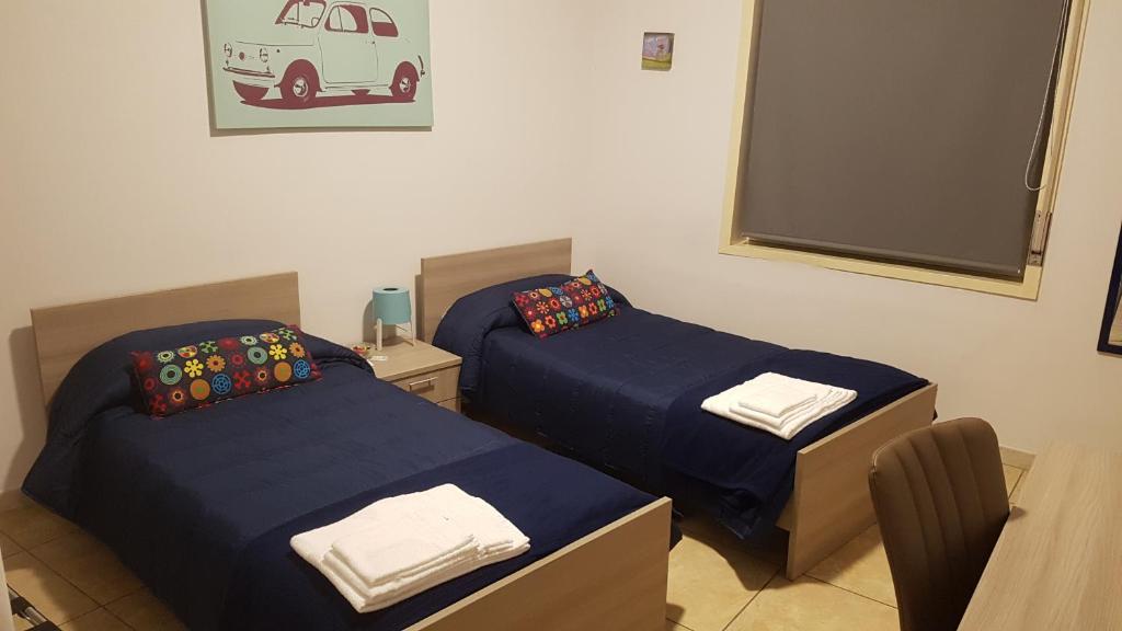 two beds are in a room with a blue wall at Etna Parking in Catania