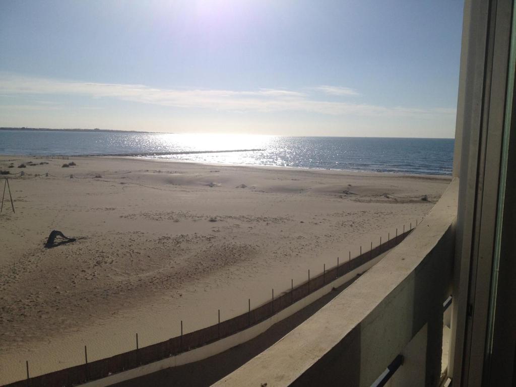 uma vista para a praia a partir de uma janela em RESIDENCE DE LA MER em Le Grau-du-Roi