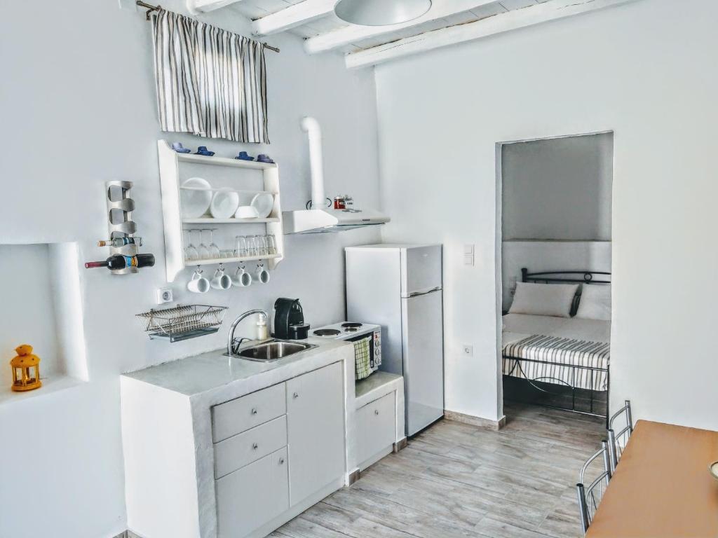 uma cozinha branca com um lavatório e um frigorífico em Sopravento House em Serifos Chora