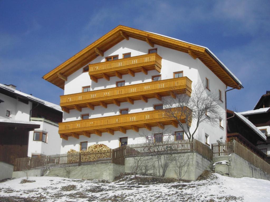 a large white building with a wooden roof at Haus Bergwelt-inklusiv Super Sommer Card in Serfaus