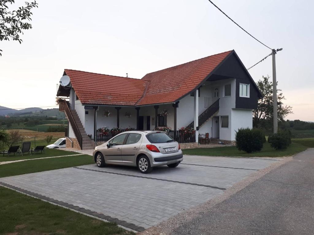 a car parked in a parking lot in front of a house at Guesthouse Andja in Smoljanac
