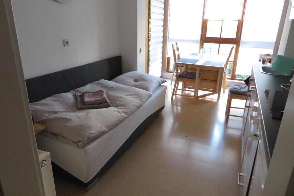 Bett in einem Zimmer mit einem Tisch und einer Küche in der Unterkunft Welcome House in Wendlingen am Neckar