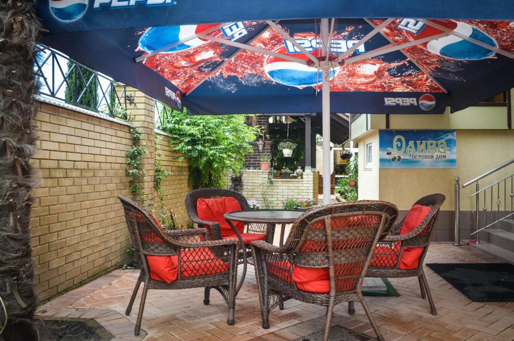 a table and chairs under an umbrella on a patio at Guest House Oliva in Adler