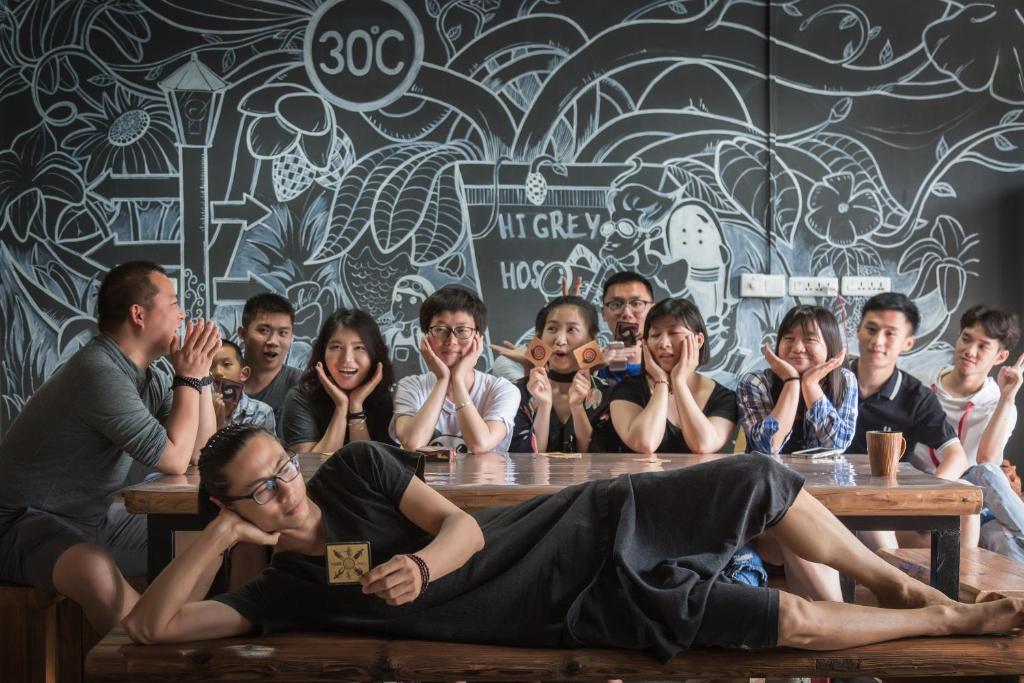 um grupo de pessoas sentadas em torno de uma mesa de madeira em Hi Grey Hostel Xingping em Yangshuo