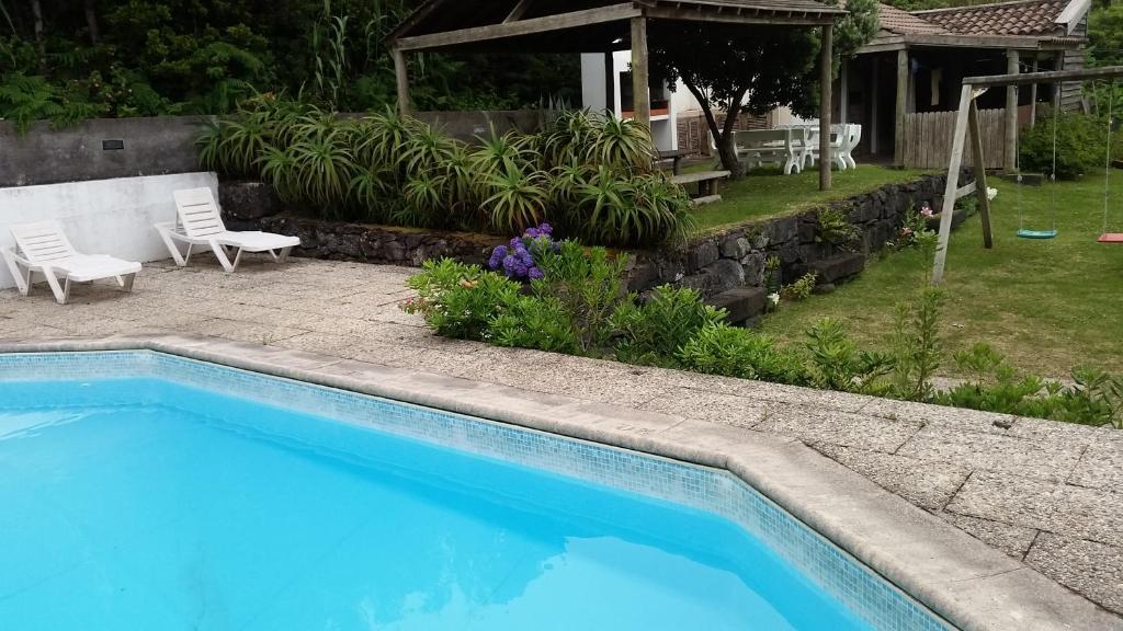 einen Pool in einem Garten mit zwei Stühlen in der Unterkunft Casal do Vulcão in Capelo