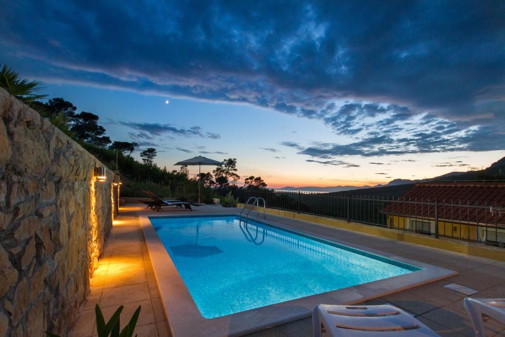 a swimming pool with a sunset in the background at HIDDEN PARADISE - Villa by Split in Žrnovnica