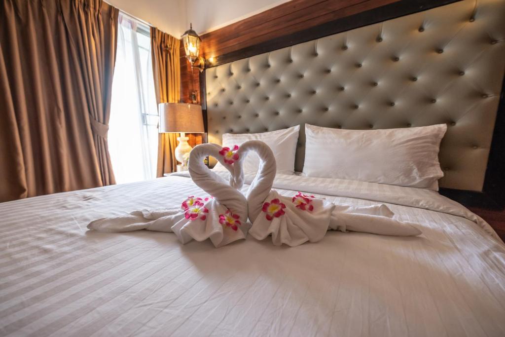 曼谷的住宿－Infinite Hotel，两个穿白色的天鹅坐在床上