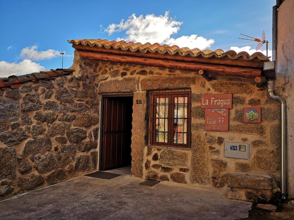 um edifício de pedra com uma porta e um sinal nele em casa rural La Fragua em Villar de Corneja