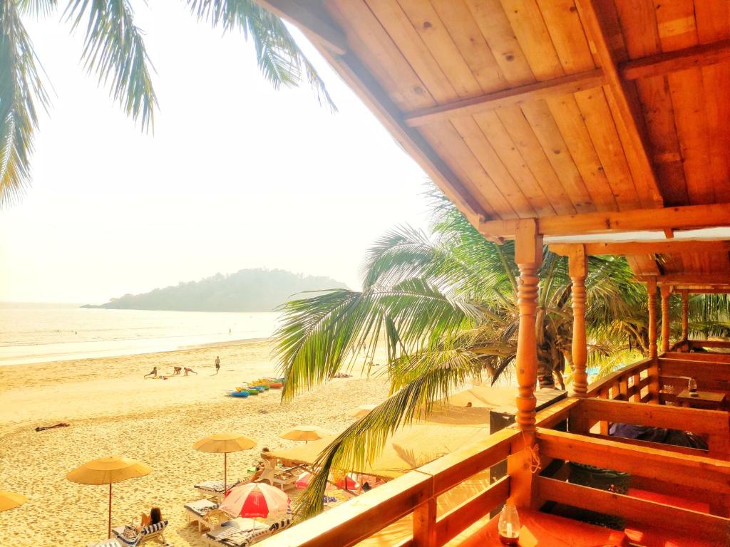 a beach with umbrellas and people on the sand at Cafe Blue in Palolem