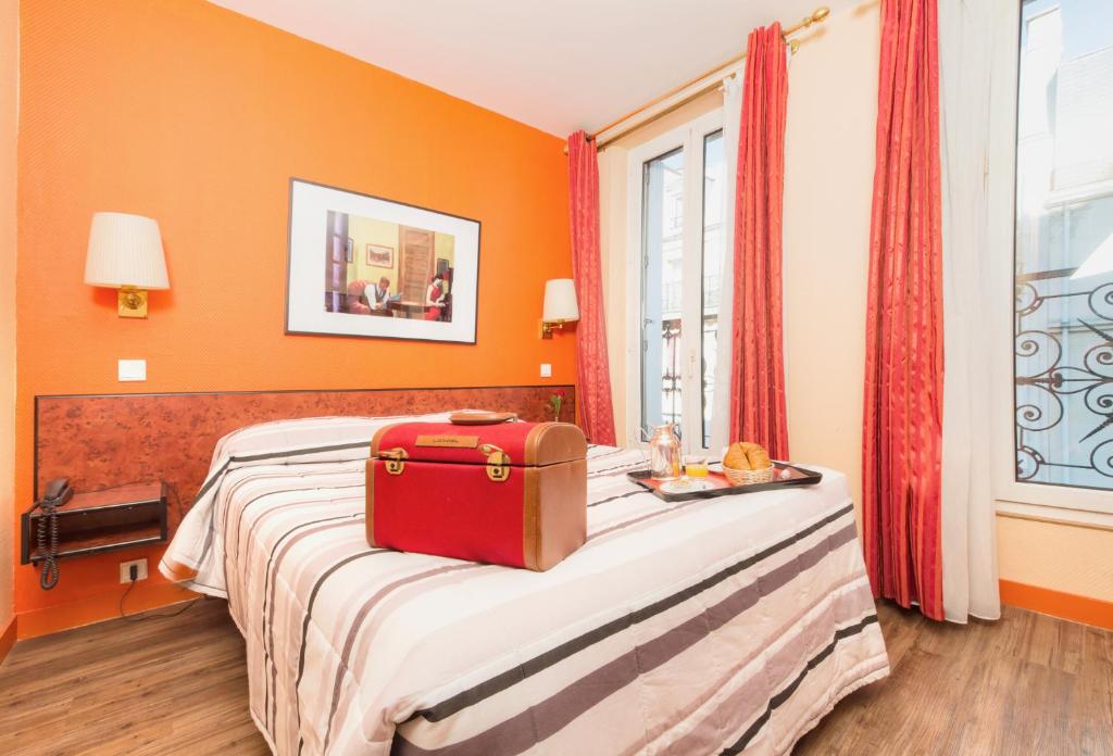 ein roter Koffer auf einem Bett in einem Zimmer in der Unterkunft Hotel Pierre Nicole in Paris