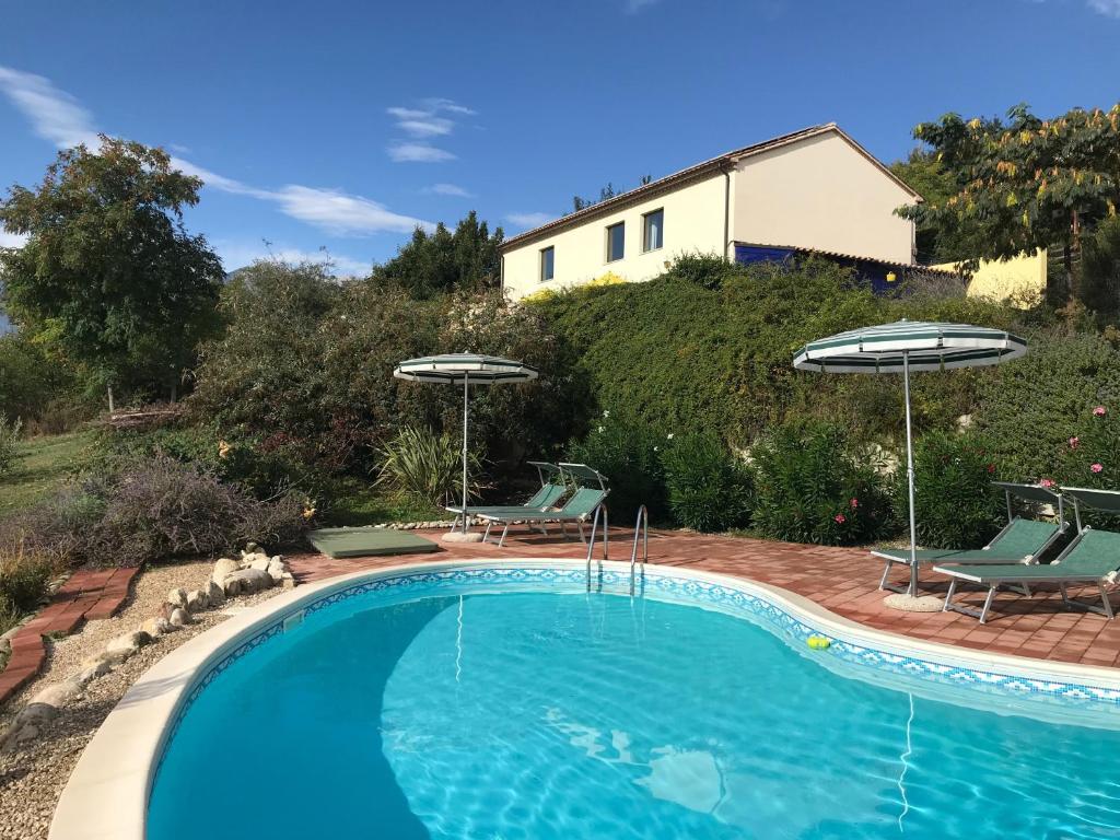 a swimming pool with two chairs and umbrellas at Villasfor2 in Casoli