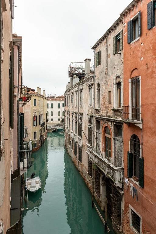 a canal between two buildings with a boat in the water at Luxury Venetian Rooms in Venice