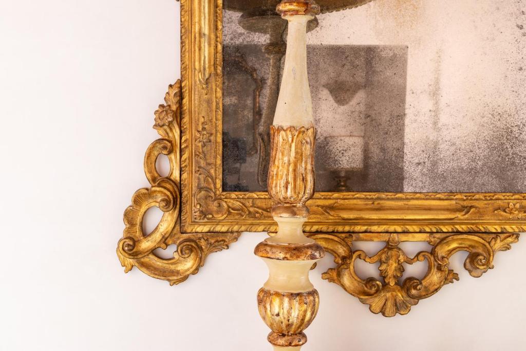 a gold mirror hanging on a wall with a vase at Luxury Venetian Rooms in Venice