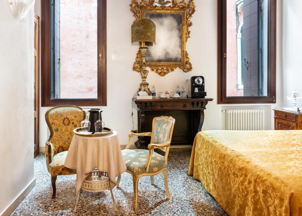 a bedroom with a bed and chairs and a table at Luxury Venetian Rooms in Venice