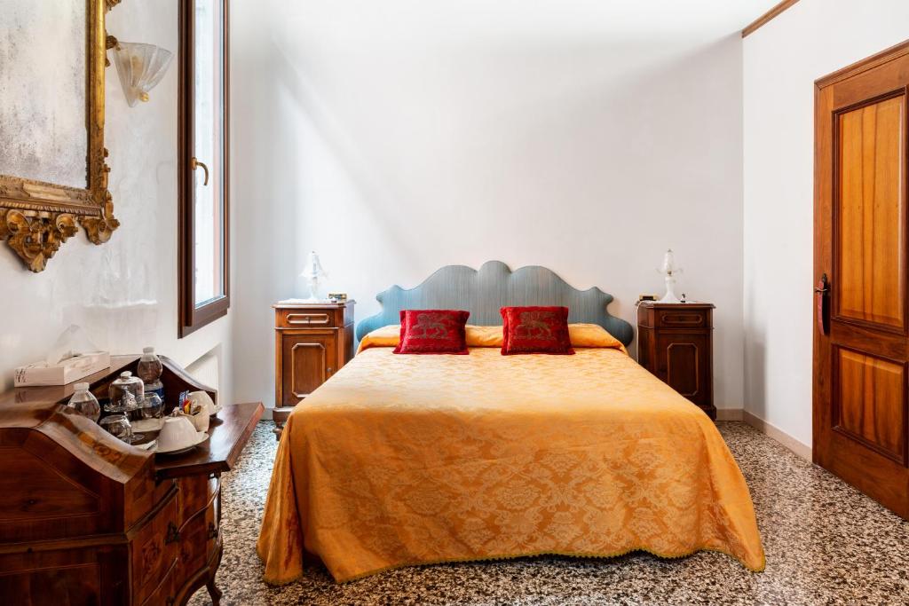 a bedroom with a bed with two red pillows at Luxury Venetian Rooms in Venice