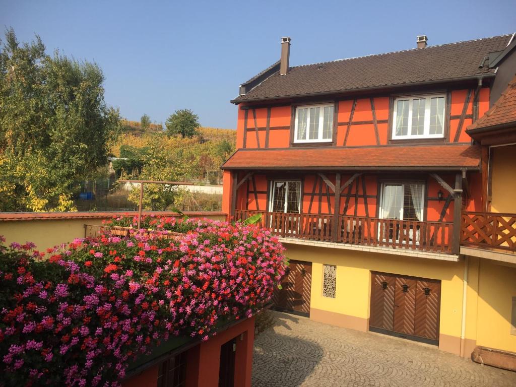 an orange and yellow house with flowers on a balcony at Gite Fruehmess in Itterswiller