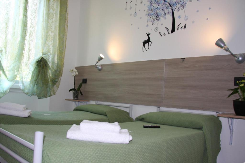 una camera con due letti verdi e una parete con un cartello di Hotel Adelchi a Milano