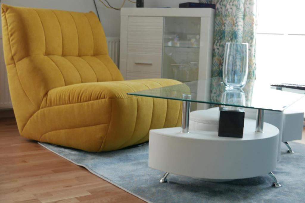 uma sala de estar com uma cadeira amarela e uma mesa de vidro em Apartament Soft 14 em Biała Podlaska