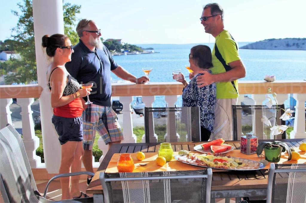 un gruppo di persone in piedi su un portico con cibo su un tavolo di Olive House a Šimuni