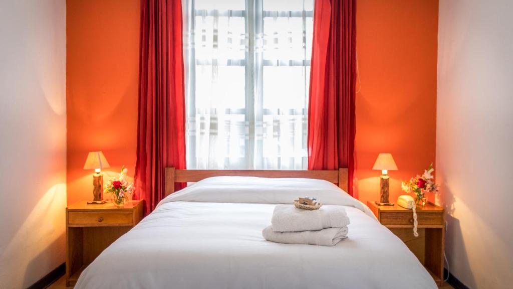 1 dormitorio con paredes de color naranja y 1 cama con toallas. en Hotel Casa Campesina en Cuzco