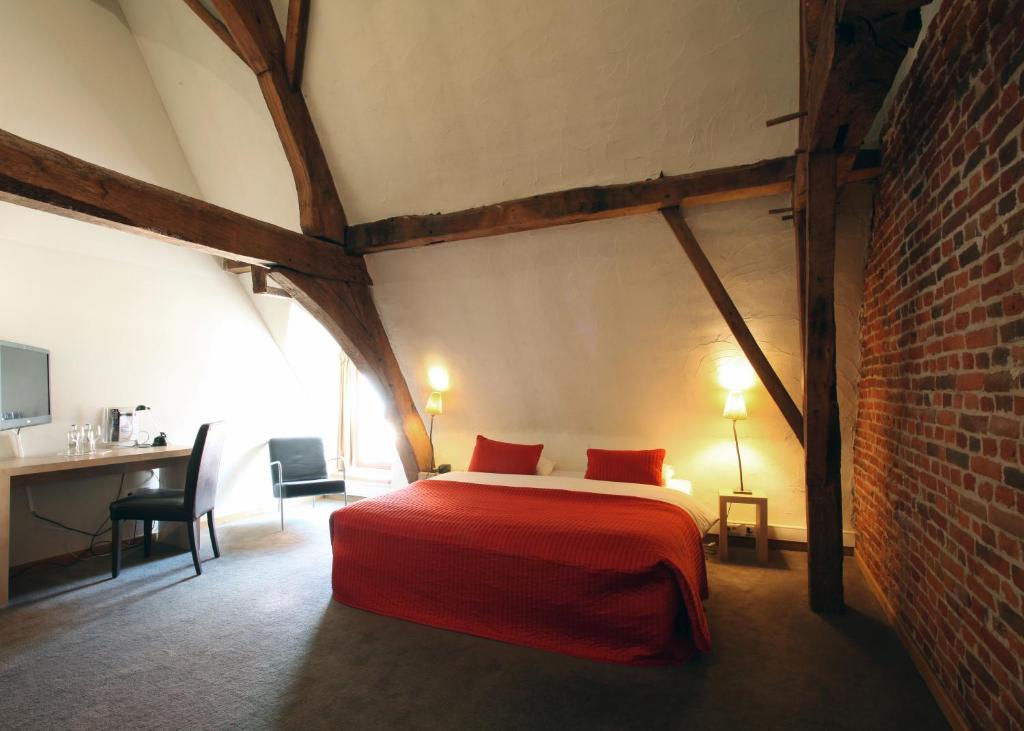a bedroom with a bed with red sheets and a brick wall at Hotel The Lodge Heverlee in Leuven