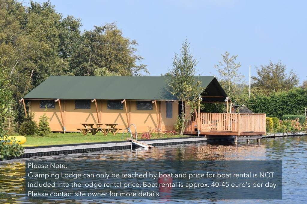 a house on the water with a sign in front of it at Glamping Amsterdam "only to be reached by boat" in Baambrugse Zuwe