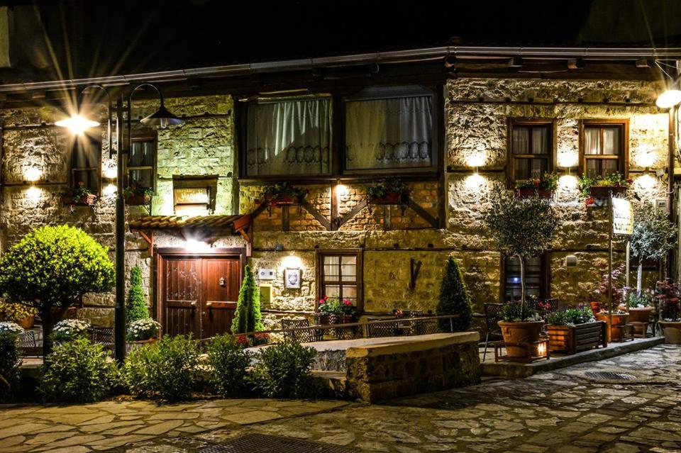 un viejo edificio de piedra con luces encendidas por la noche en Hagiati Guesthouse en Edessa