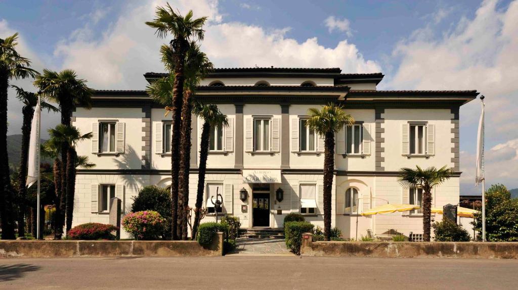 a white house with palm trees in front of it at Villa Garni Gardenia in Caslano