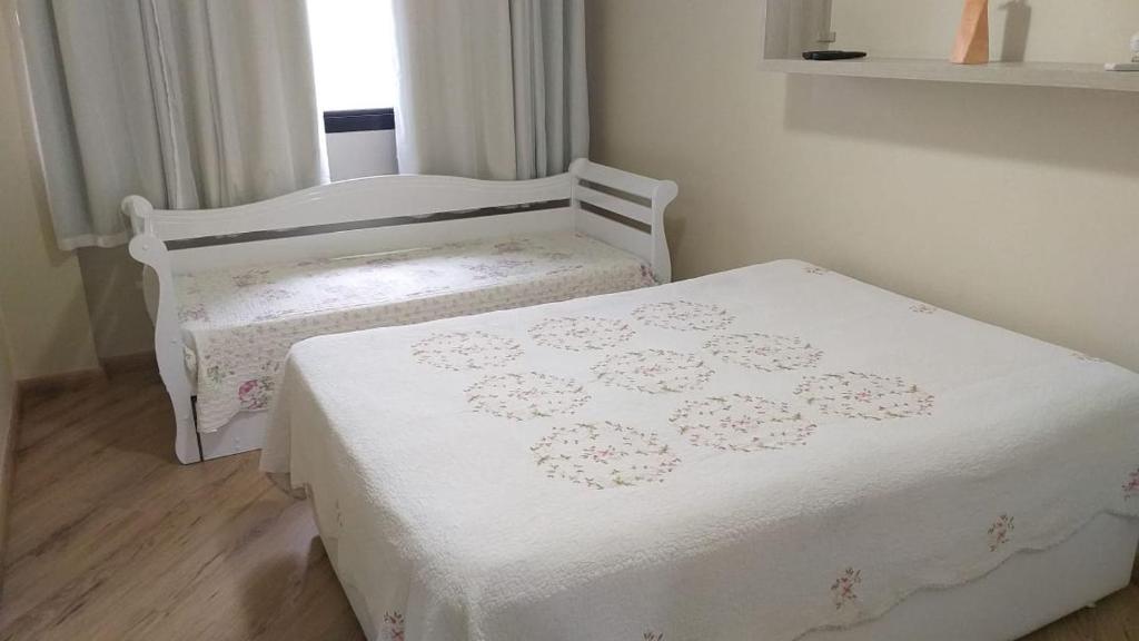 1 dormitorio con 2 camas con sábanas blancas y ventana en Angra Super Luxo, en Mangaratiba