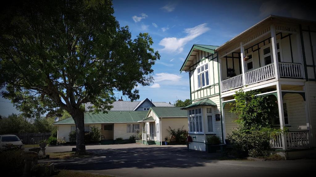 una grande casa bianca con un albero di fronte di Chanel Court Motel a Masterton