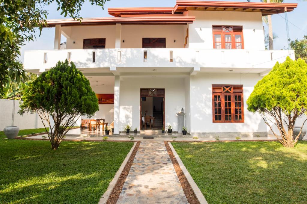 a white house with a lawn in front of it at Villa Manali in Hikkaduwa