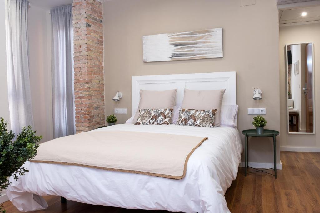 1 dormitorio con 1 cama grande con sábanas y almohadas blancas en Bienvenidos Rooms Xàtiva, en Xàtiva