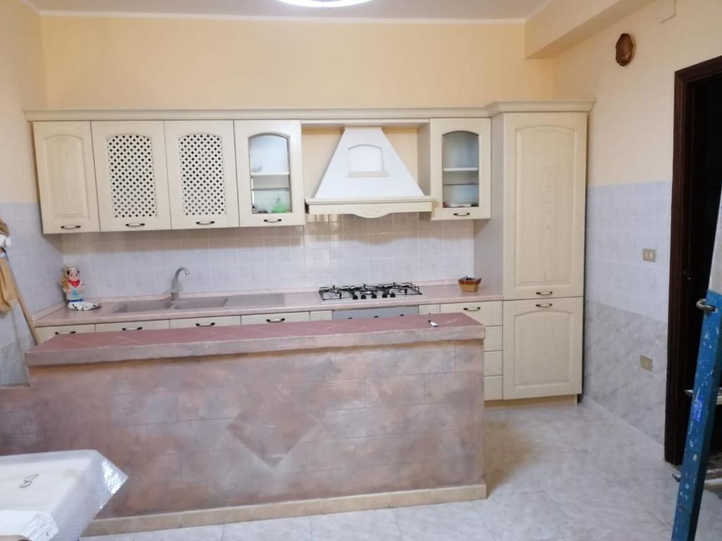 una cocina con armarios blancos y fregadero en Casa Staropoli, en Sciconi