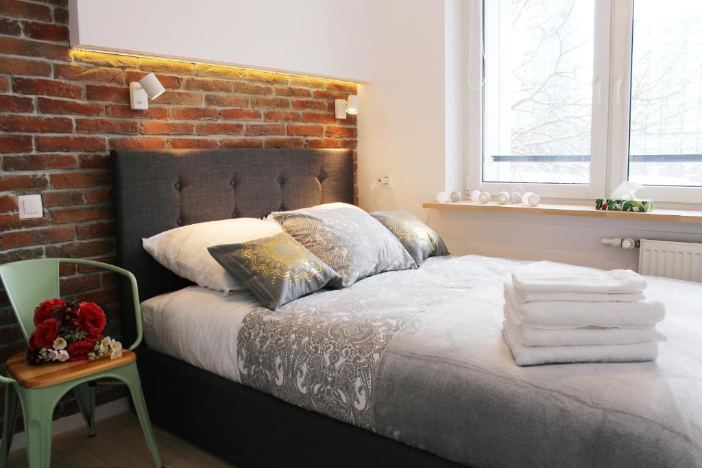 sypialnia z łóżkiem z ceglaną ścianą w obiekcie Comfy with great city view by Cooee Apartments w Warszawie