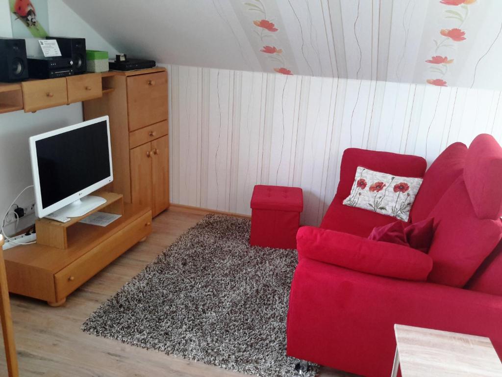 salon z czerwoną kanapą i telewizorem w obiekcie Appartement Ferienwohnung Vogel w mieście Hilchenbach