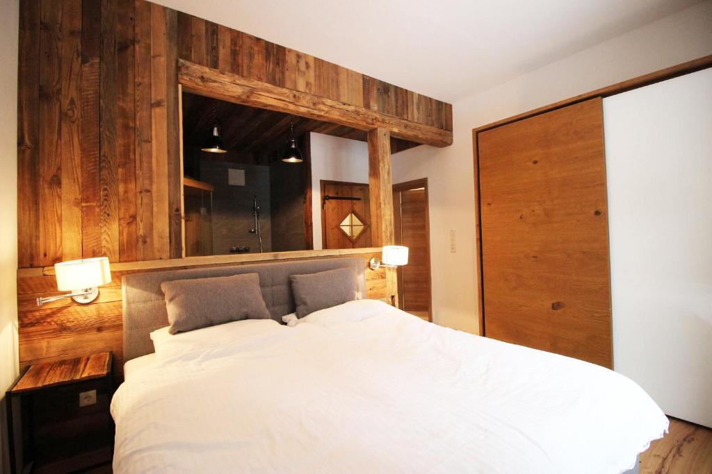 a bedroom with a white bed with a wooden wall at Alpengasthof Krische in Murau