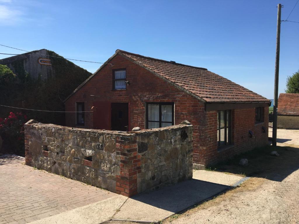 a brick house with a stone wall in front of it at New Stable Cottage in Cowes