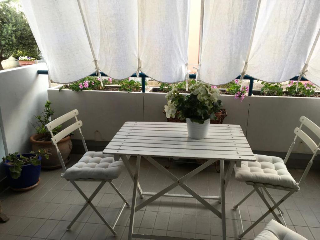 LA CASA DEL MARE في فانو: طاولة وكرسيين على شرفة مع ستائر بيضاء
