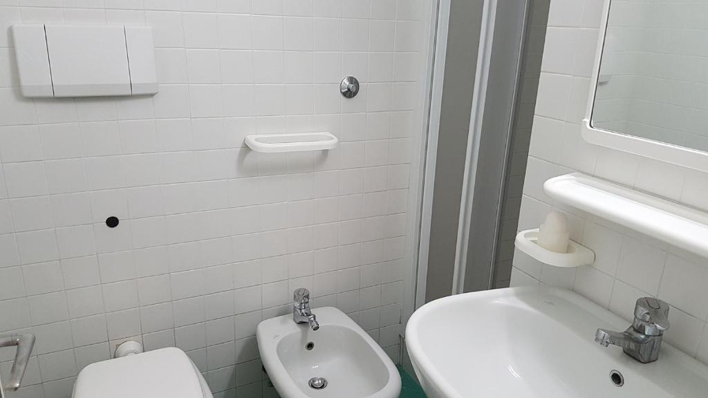 a white bathroom with a toilet and a sink at Residence Capobianco in Portoferraio