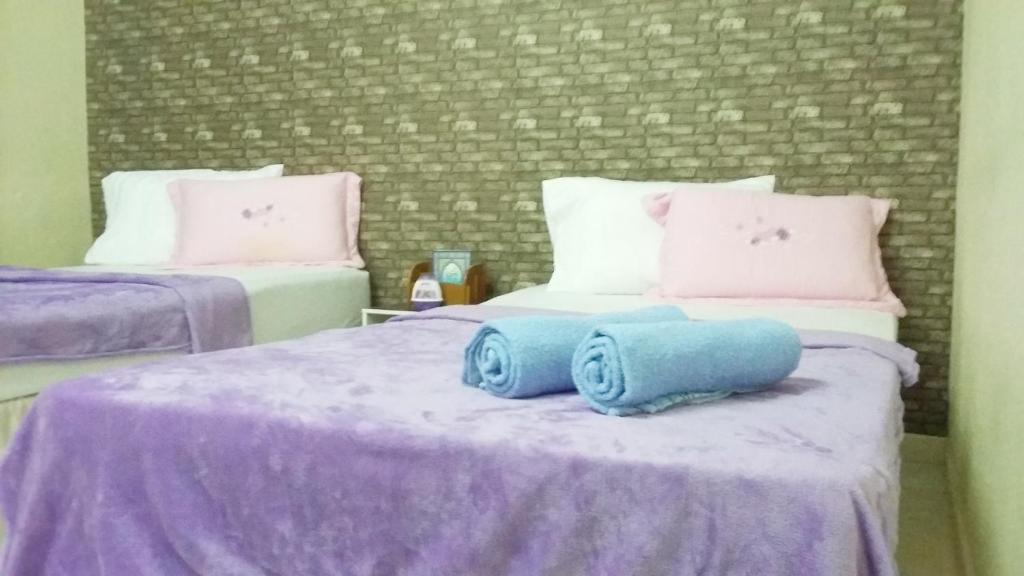 um quarto com 2 camas com lençóis e almofadas roxos em Kayangan Homestay Perlis a Islamic House em Kangar