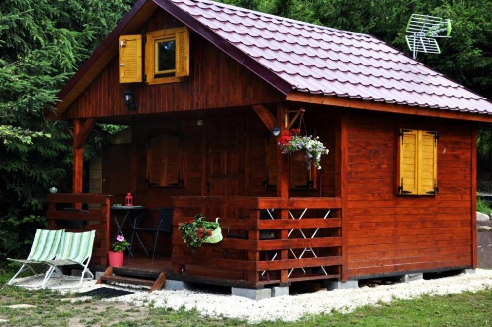 eine kleine Holzhütte mit gelben Fenstern und einem Stuhl in der Unterkunft Acapulco Domki Radków in Radków