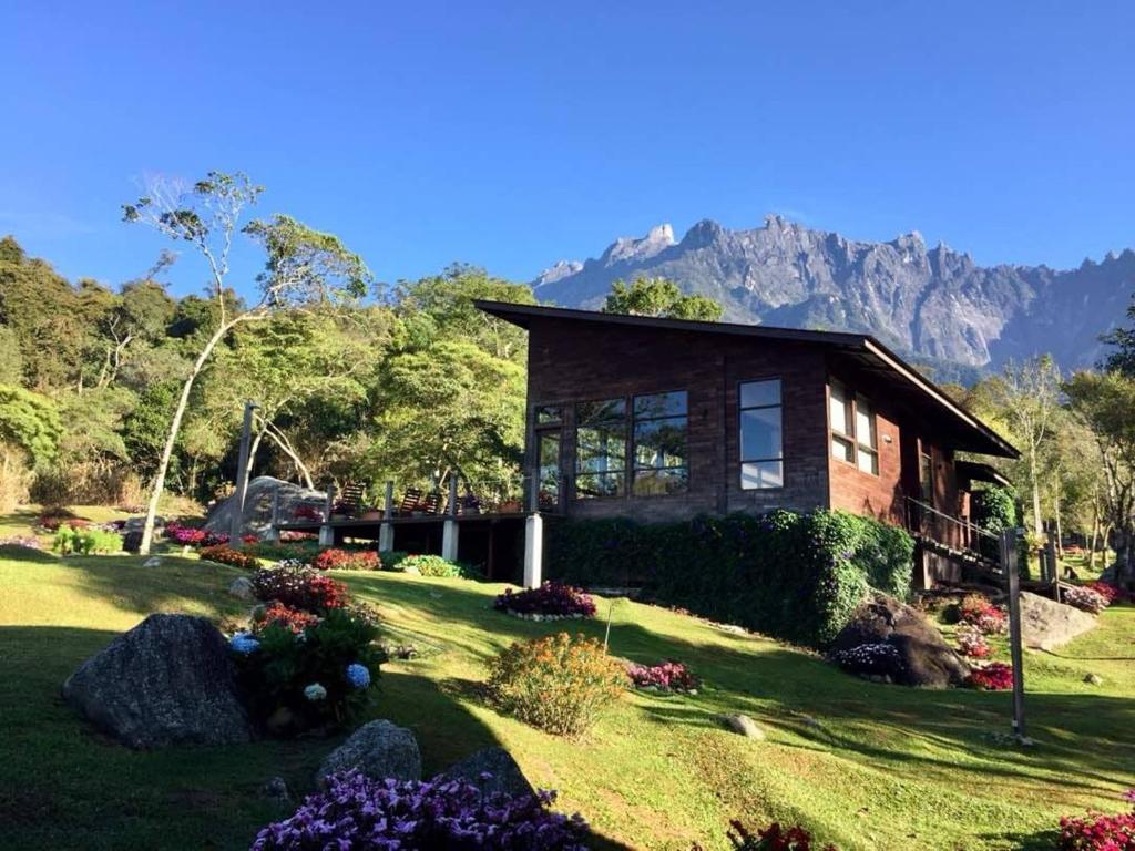a house on a lawn with mountains in the background at Spring Garden in Kundasang